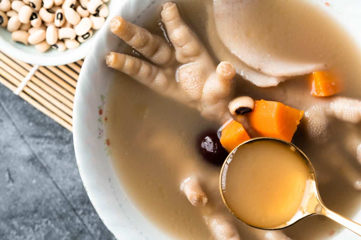 Spoon of chicken foot soup in a bowl.
