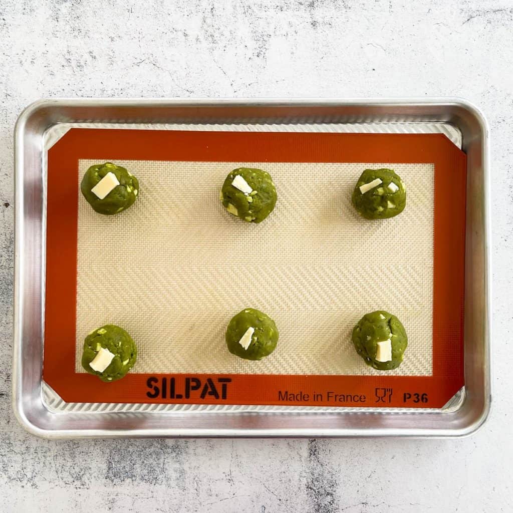 Matcha cookie dough balls on a tray.