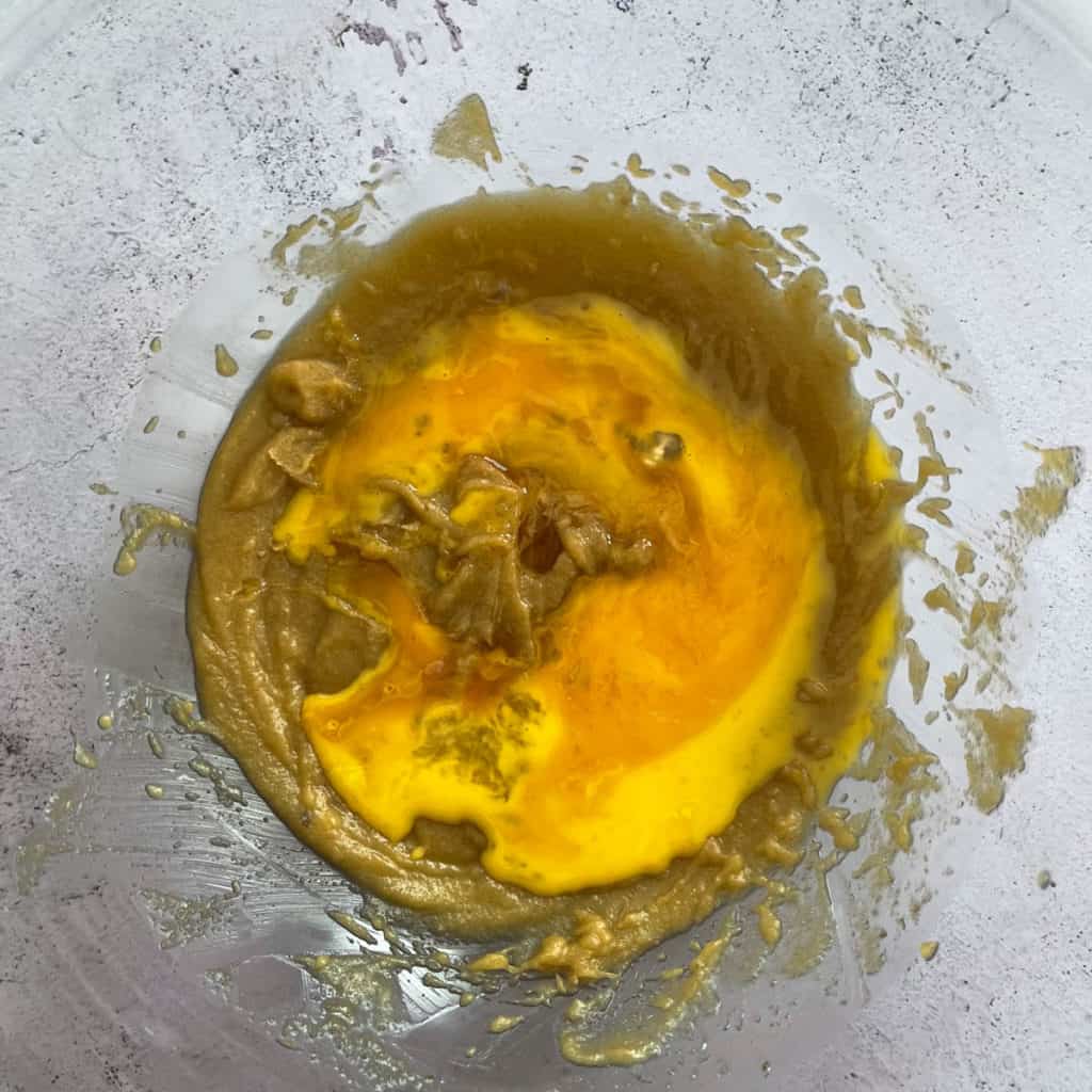 Butter, sugars and eggs combined in a bowl.