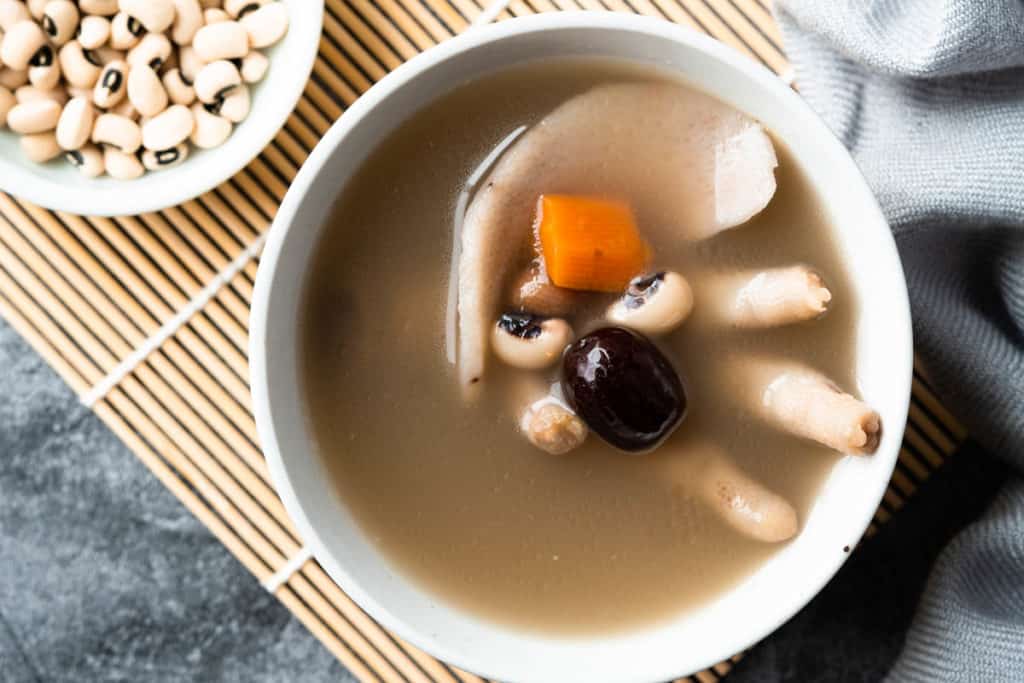 Bowl of chicken foot soup with carrot and red dates.