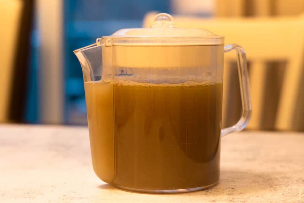 Chicken foot soup in a broth skimmer pitcher.