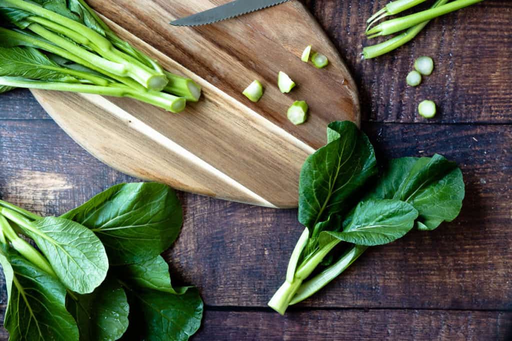 Raw yu choy stalks and leaves on a table.