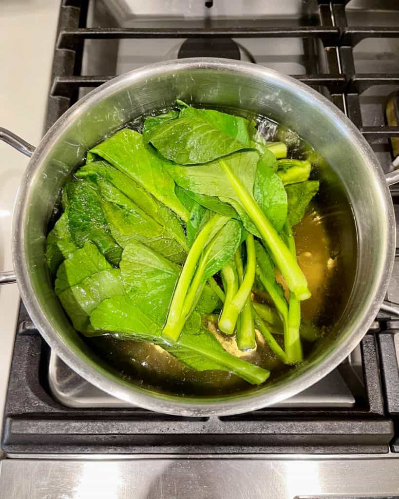 Submerged yu choy fully in blanching water.