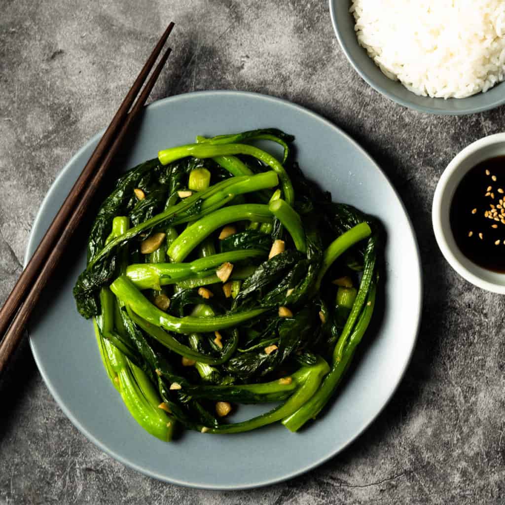 Plate of yu choy with rice and dipping sauce.