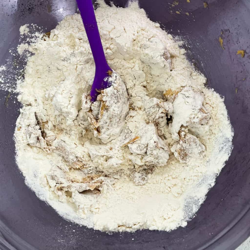 Spatula gently combining flour with creamed butter and sugar.