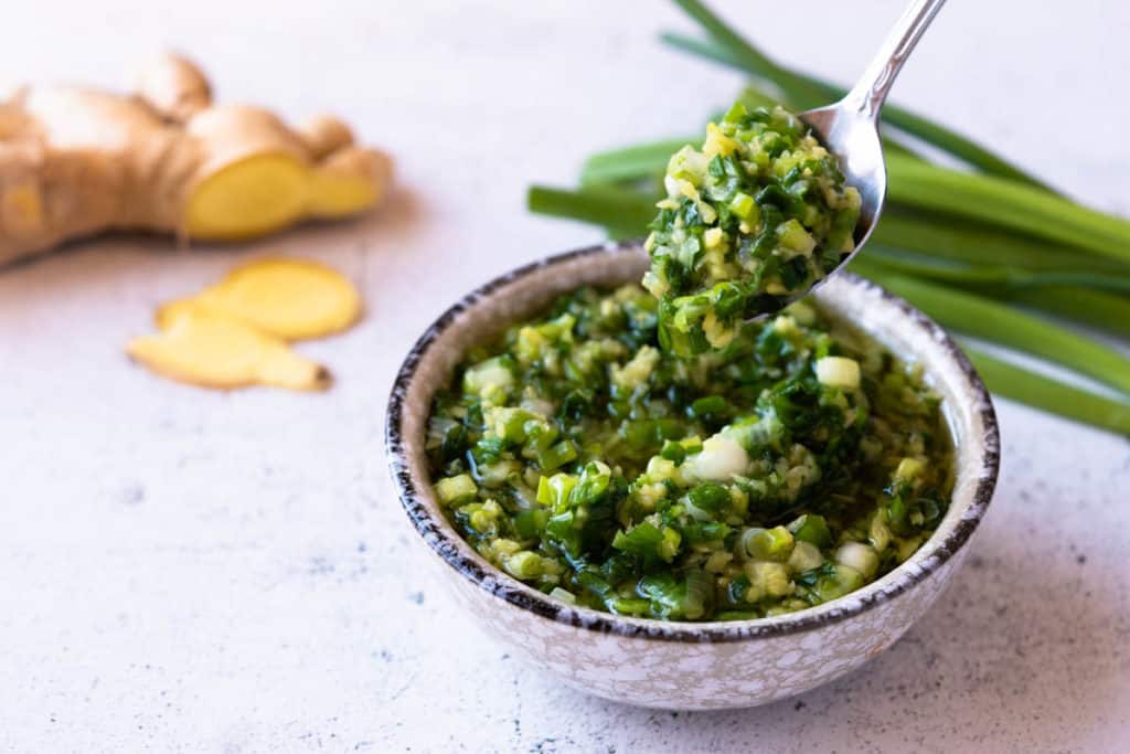 Ginger scallion sauce spooned from a bowl.