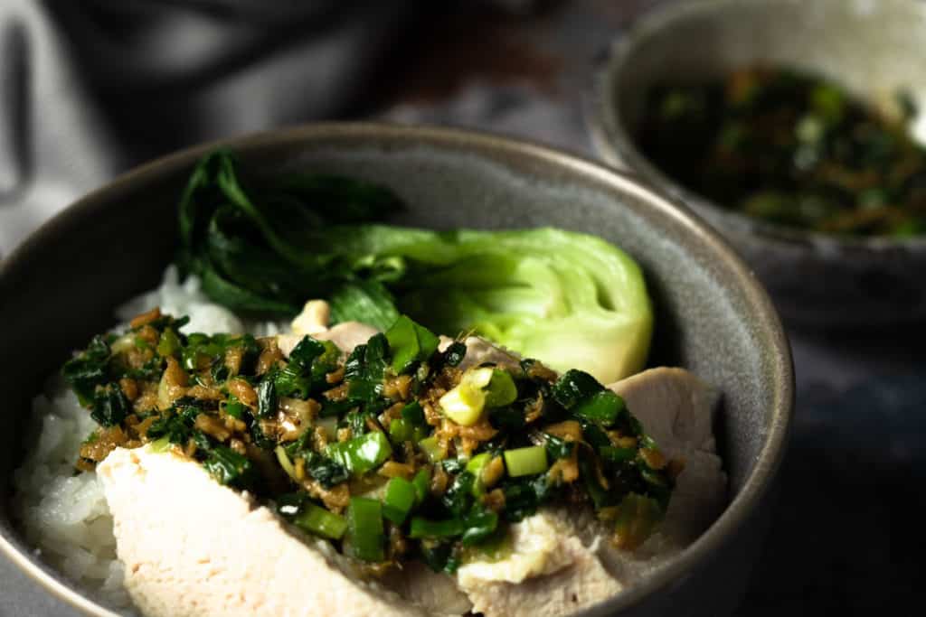 Close up of ginger scallion sauce over chicken breast and bok choy.