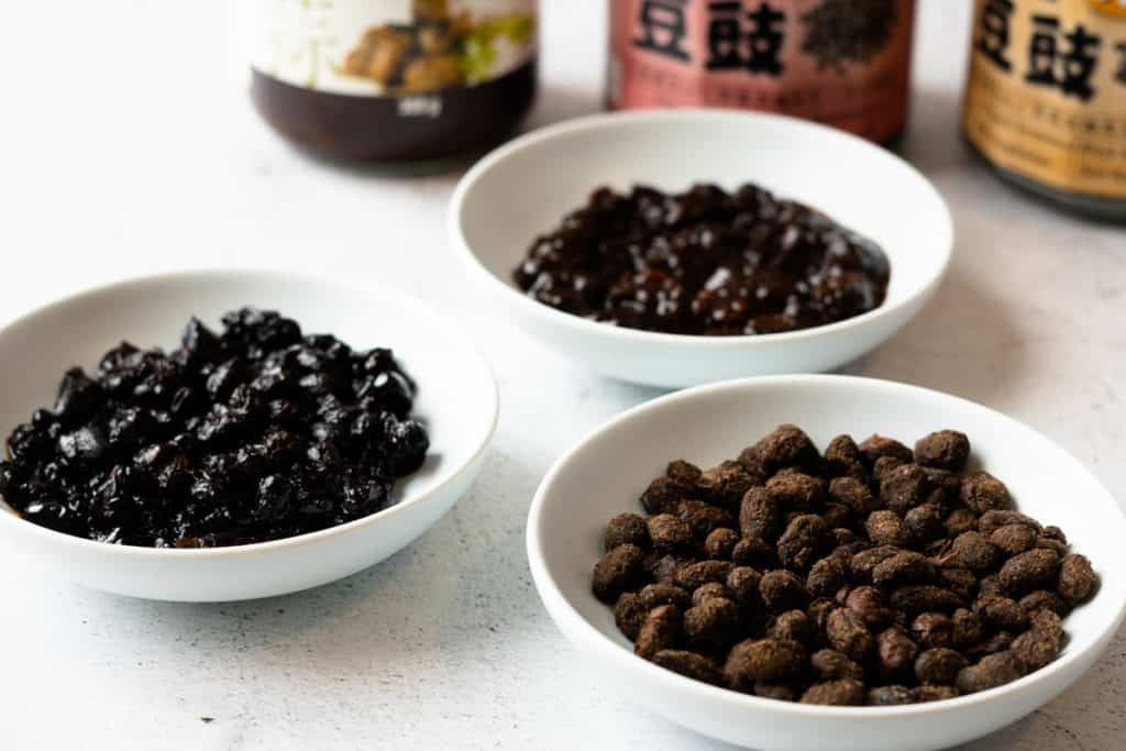 Closeup of dry and wet whole black beans and black bean sauce.