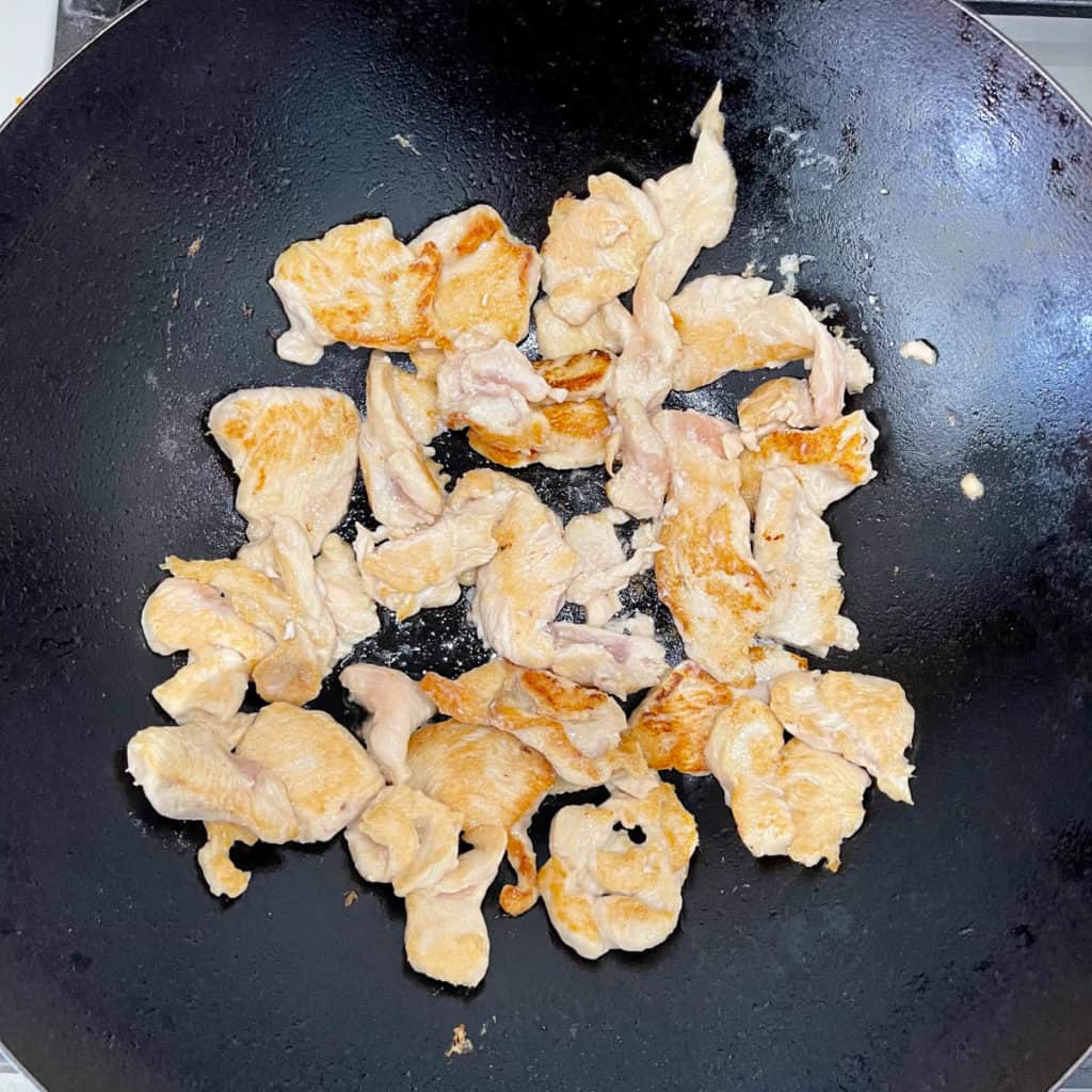 Pan seared slices of chicken breast in a wok.