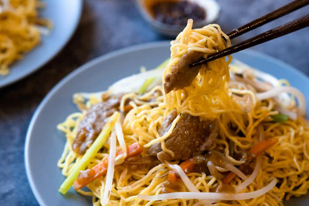 Chow mein noodles picked up by chop sticks.