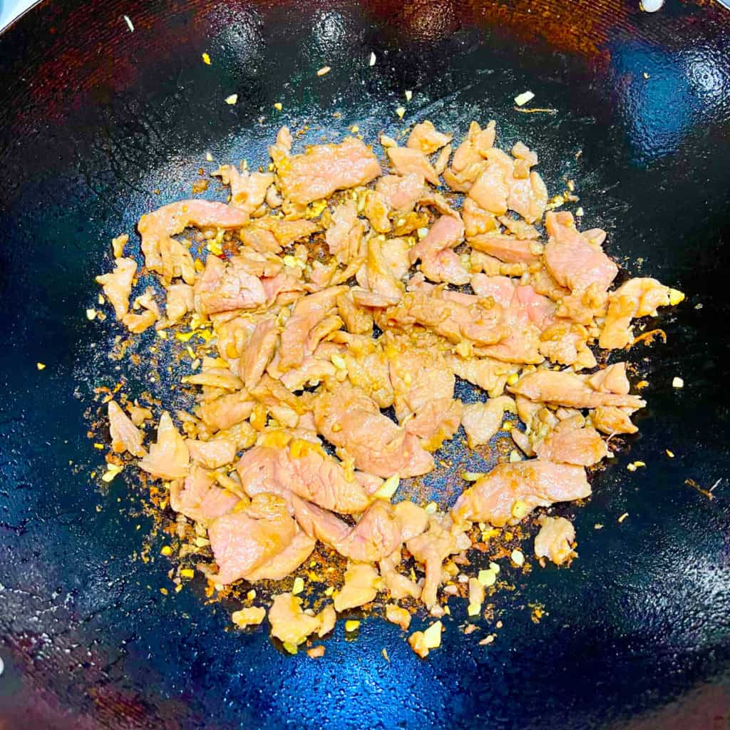 Pork tenderloin cooked and changed color in a wok.