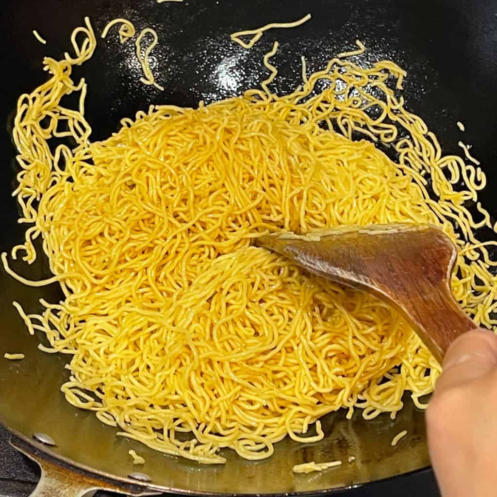 Chow mein frying lightly in oil in a wok.