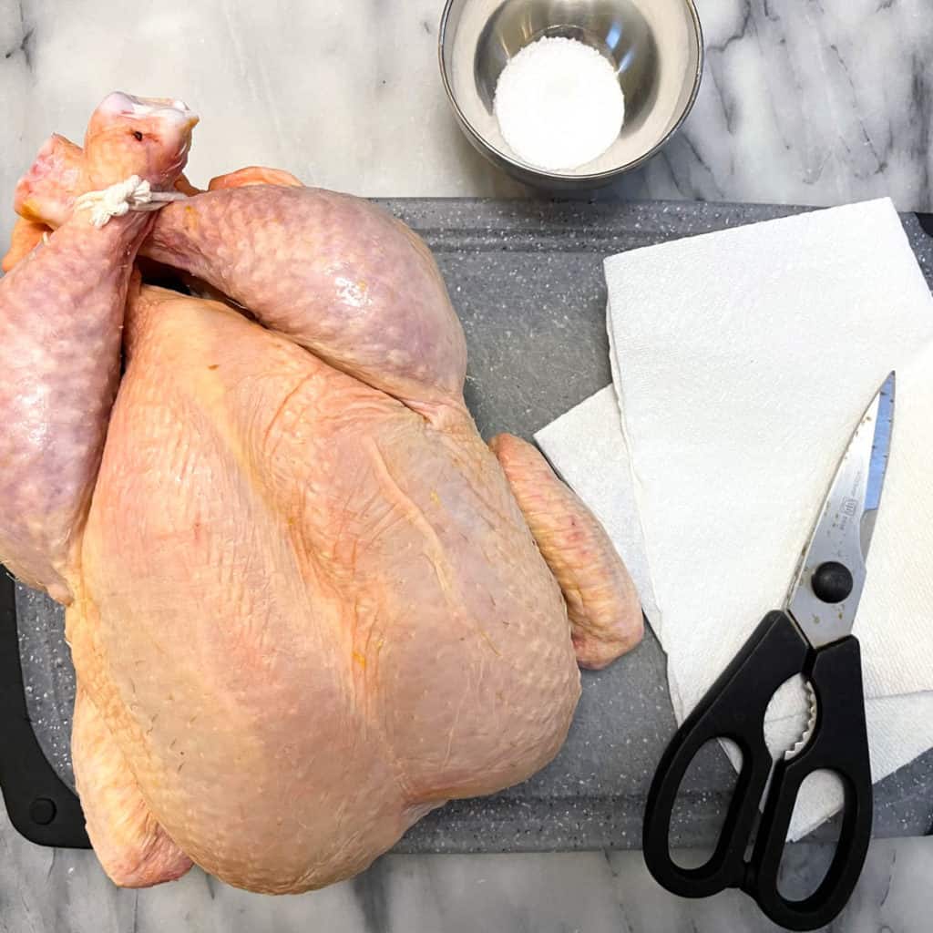 Spatchcock a chicken with kitchen shears and a knife.