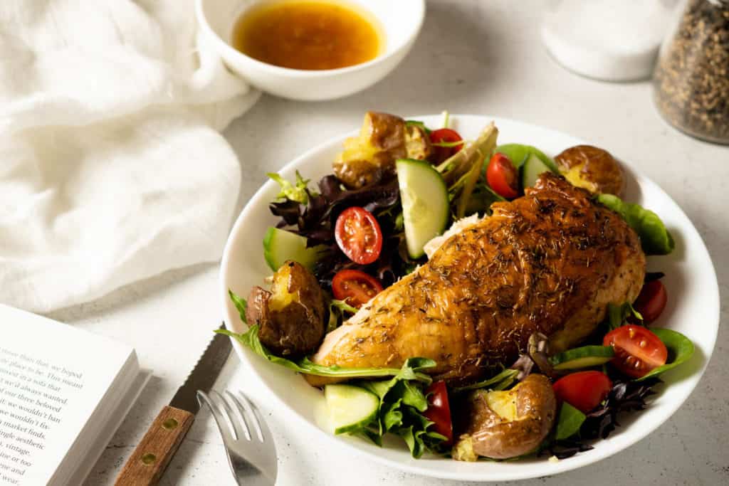Whole roasted chicken breast on a bed of greens.