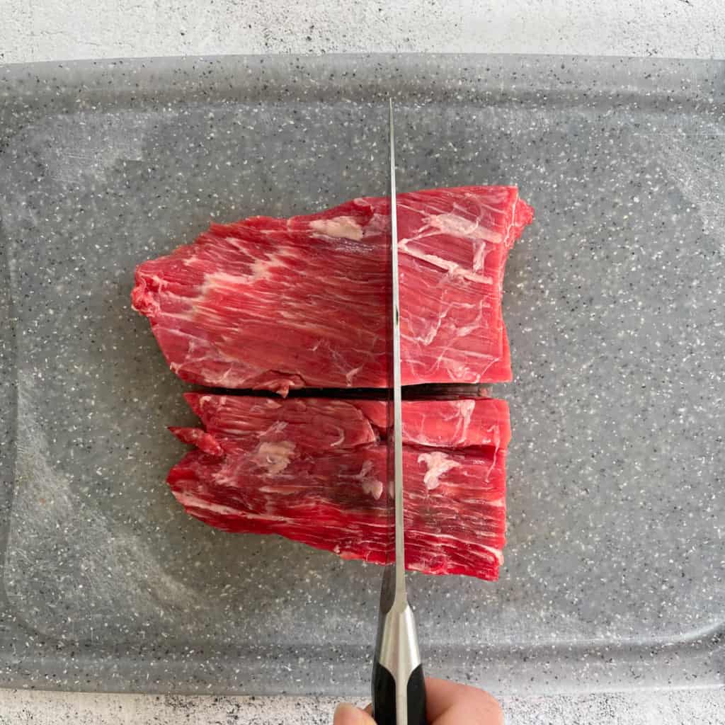 Beef flank with knife slicing against the grain.