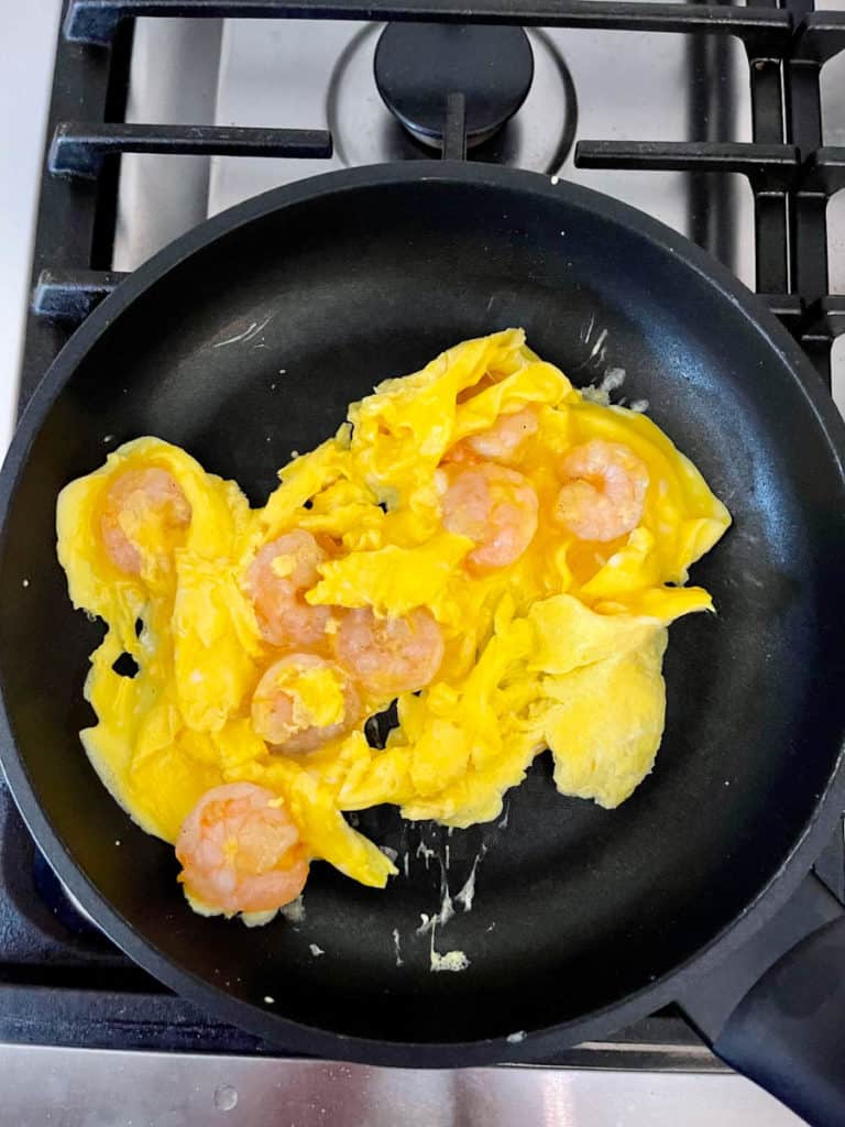 Shrimp omelet done cooking with some watery egg on top.