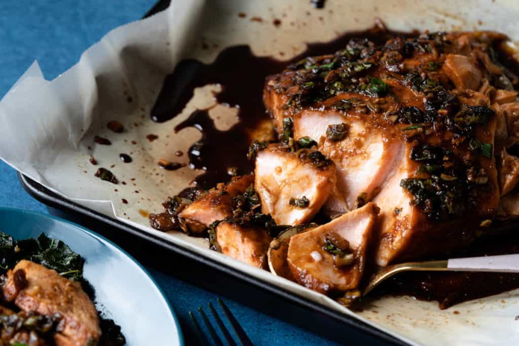 Flaked maple soy salmon fillet on a shallow baking pan with parchment paper. 
