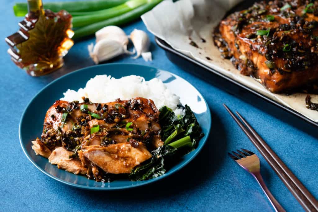 Soy maple salmon portion served with a side of rice and greens.