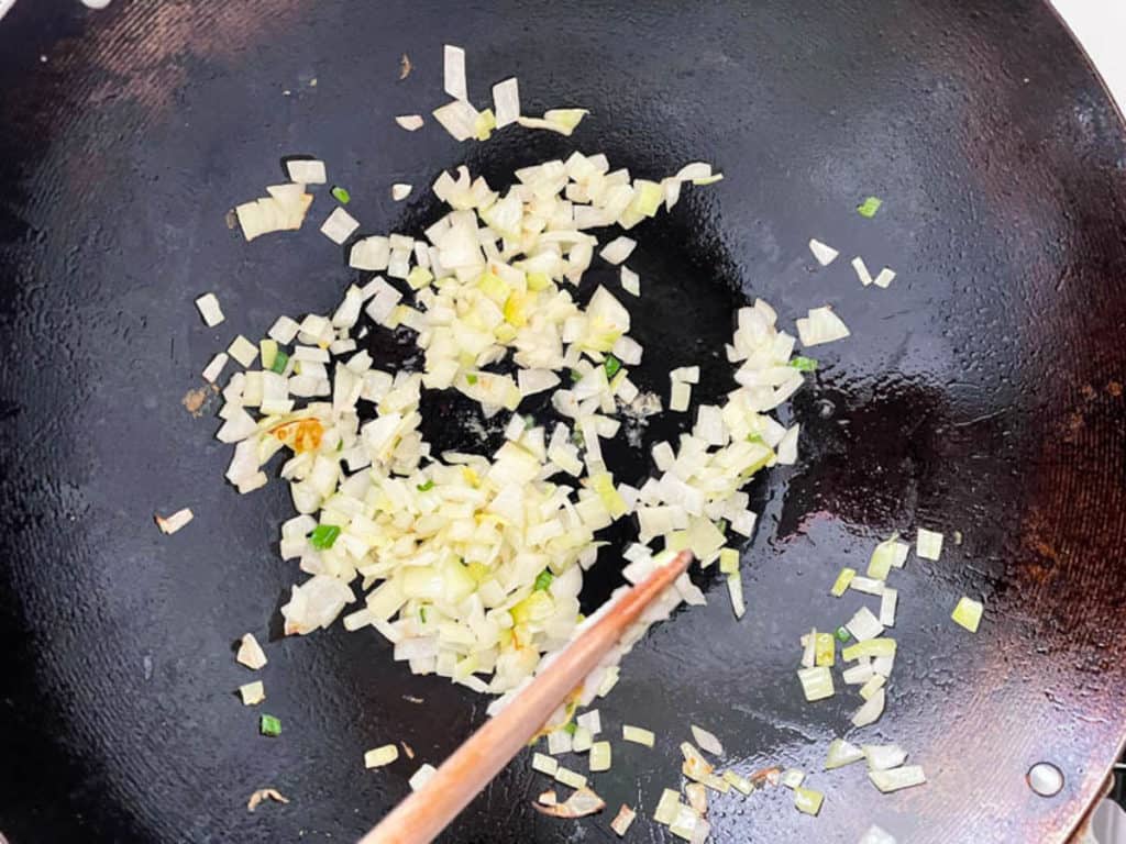 Frying onions till their translucent in a wok.