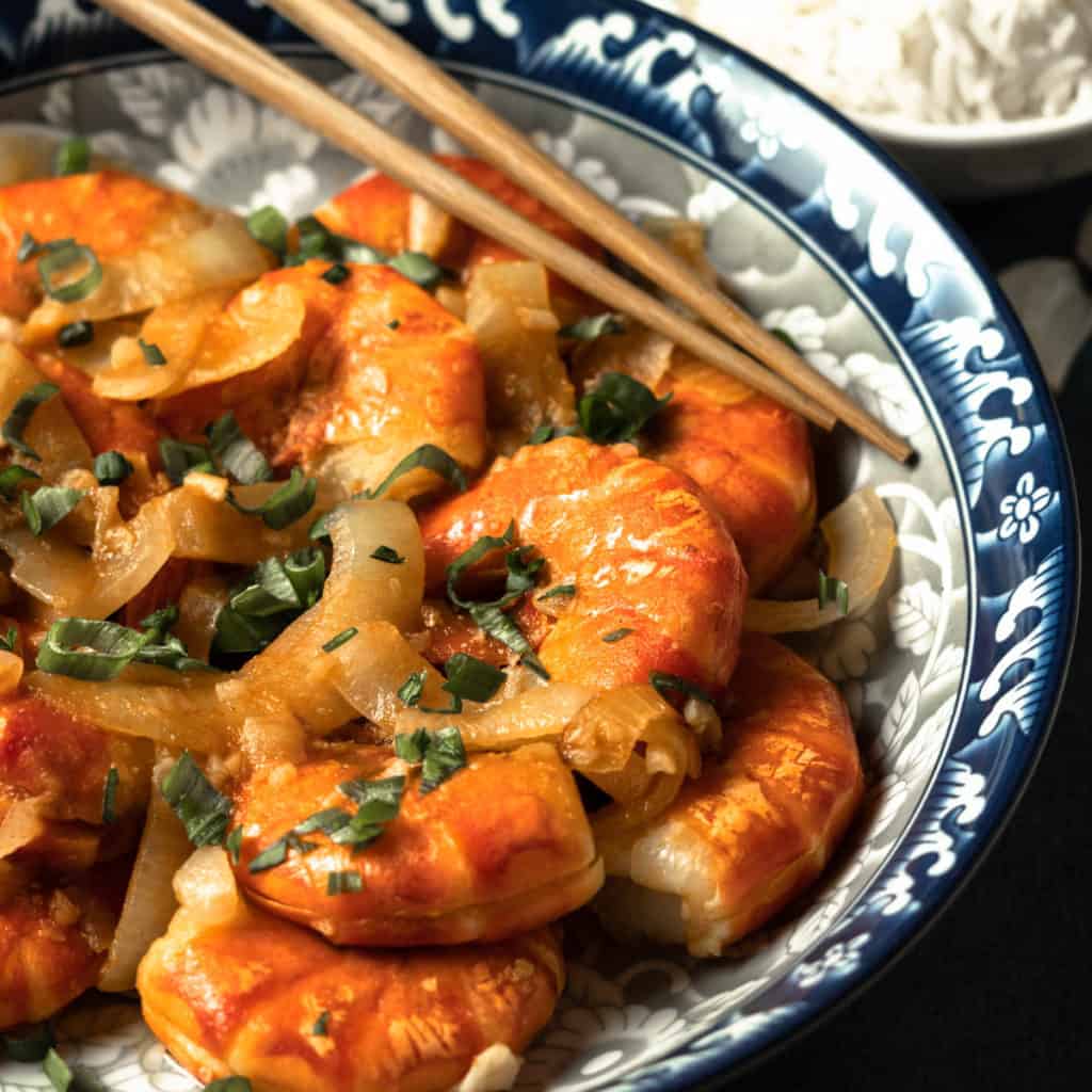 Close up of stir fried shrimp in ketchup sauce on a plate.