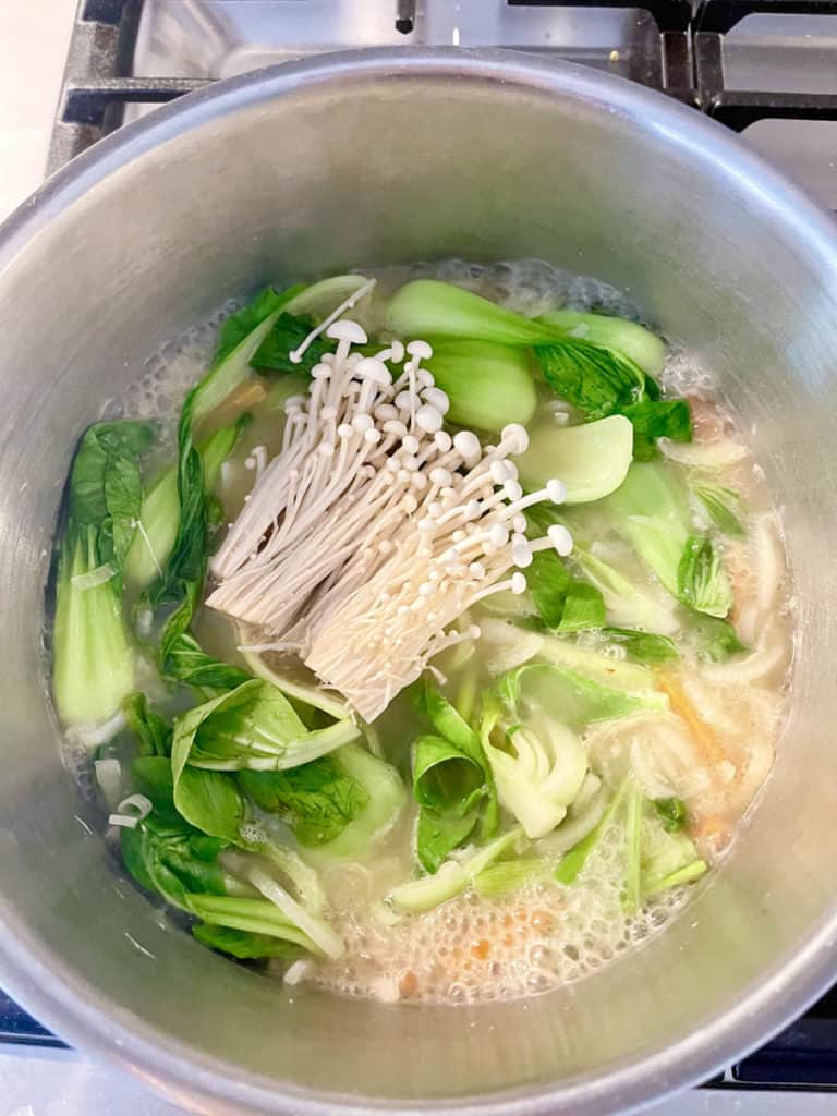 Added enoki mushrooms to broth in simmering pot.