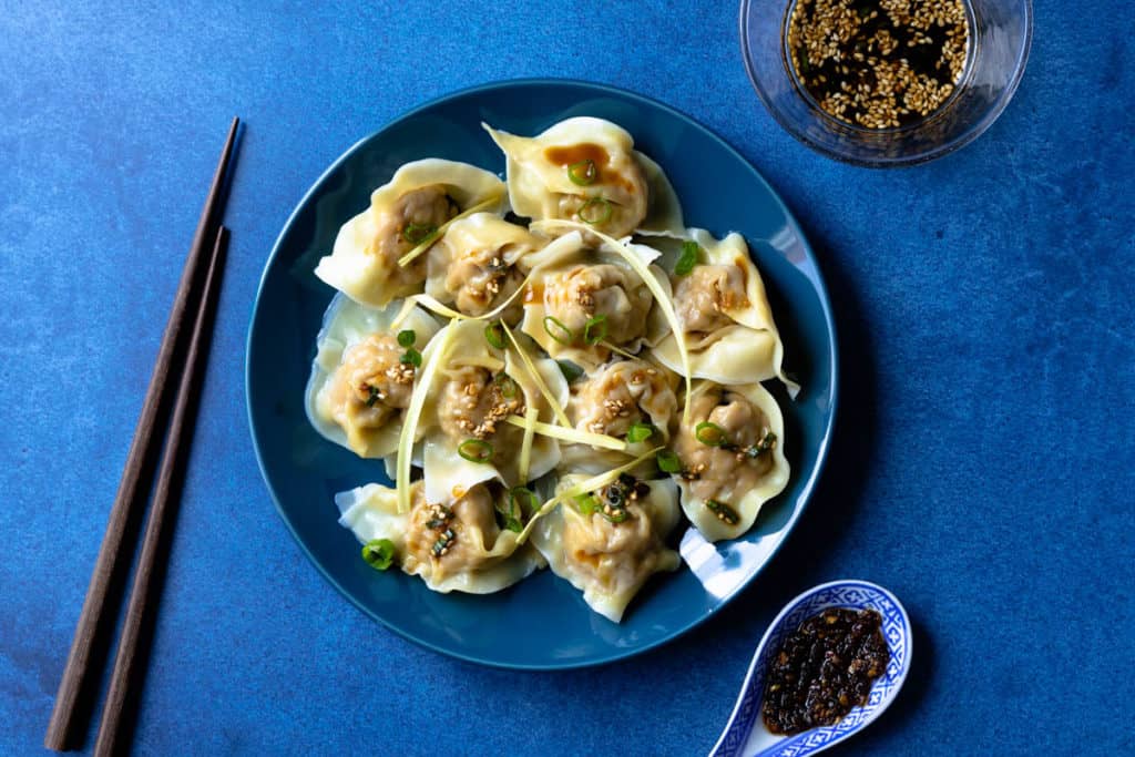 Plate of wontons drizzled with dipping sauce.