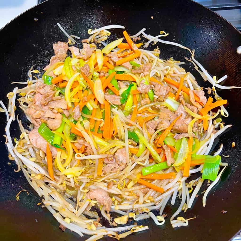 Pork chow mein ingredients tossed in a wok.