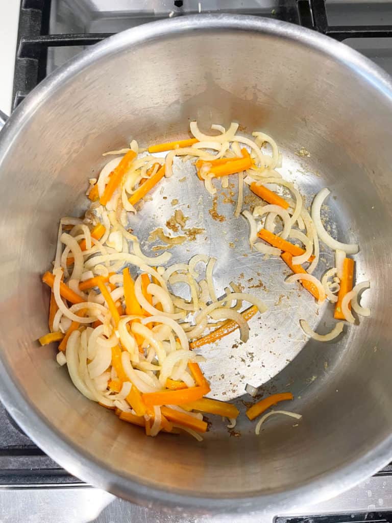 Sautéed carrot and onion in a pot for broth.