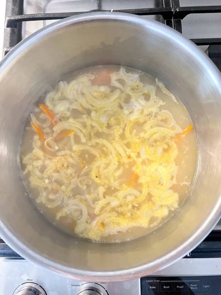 Simmering broth with onions and carrots.