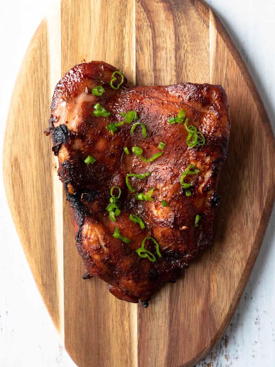 Chicken steak resting on a wooden board.