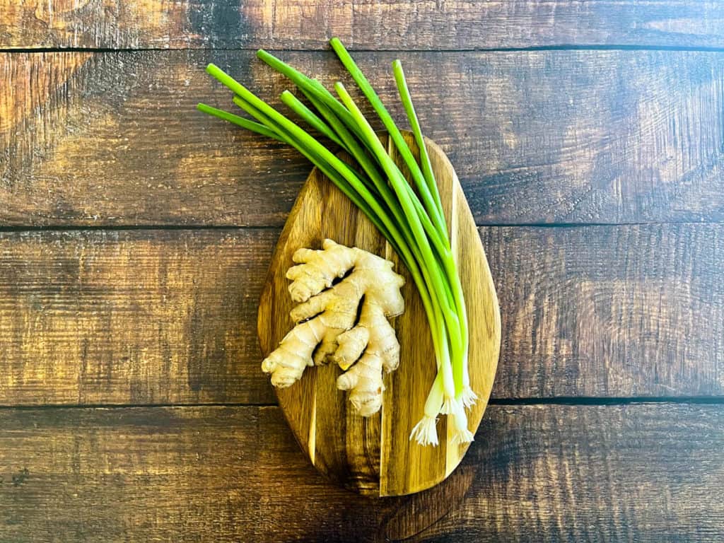 Ginger root with scallions on a cutting board.