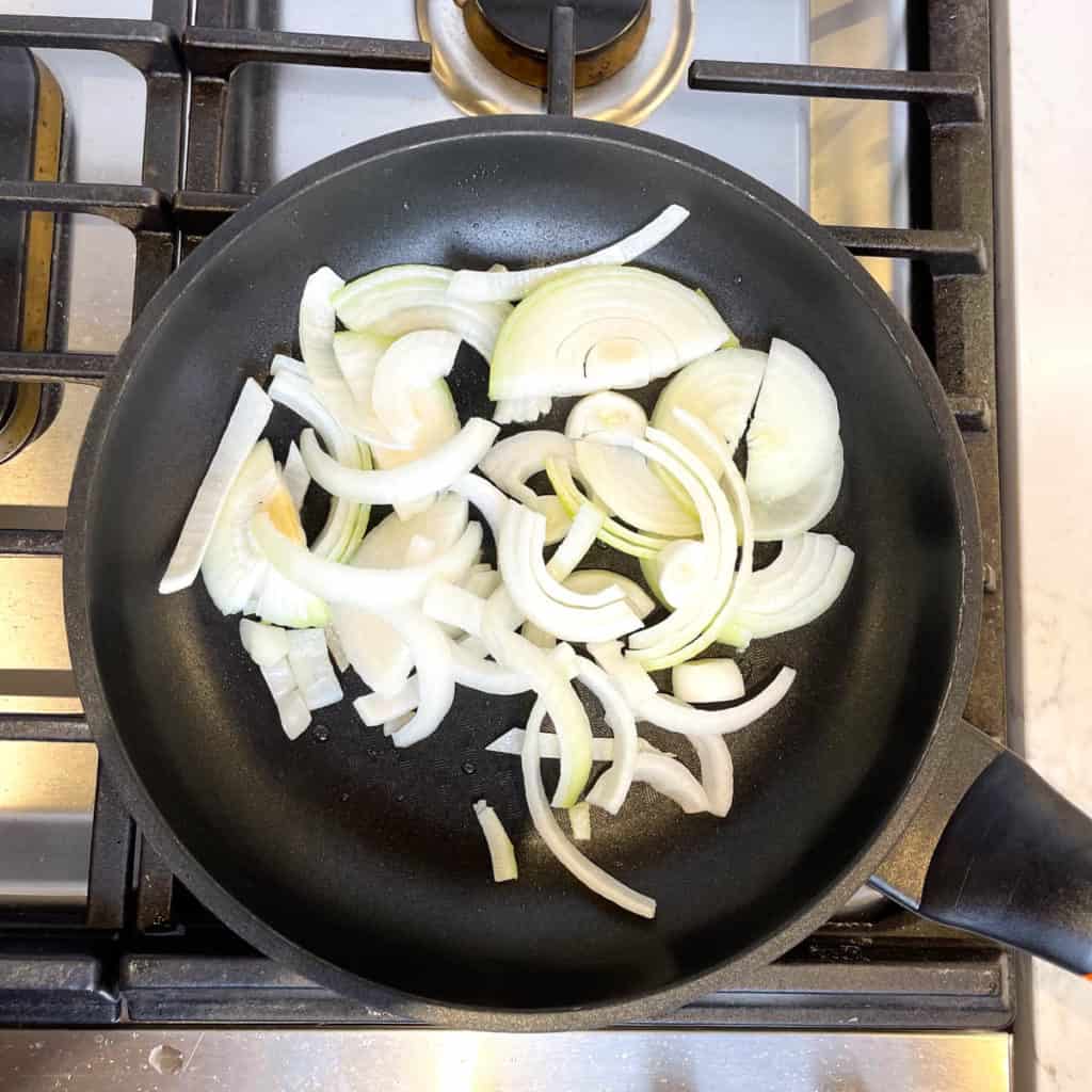 Sliced onions frying in a pan.