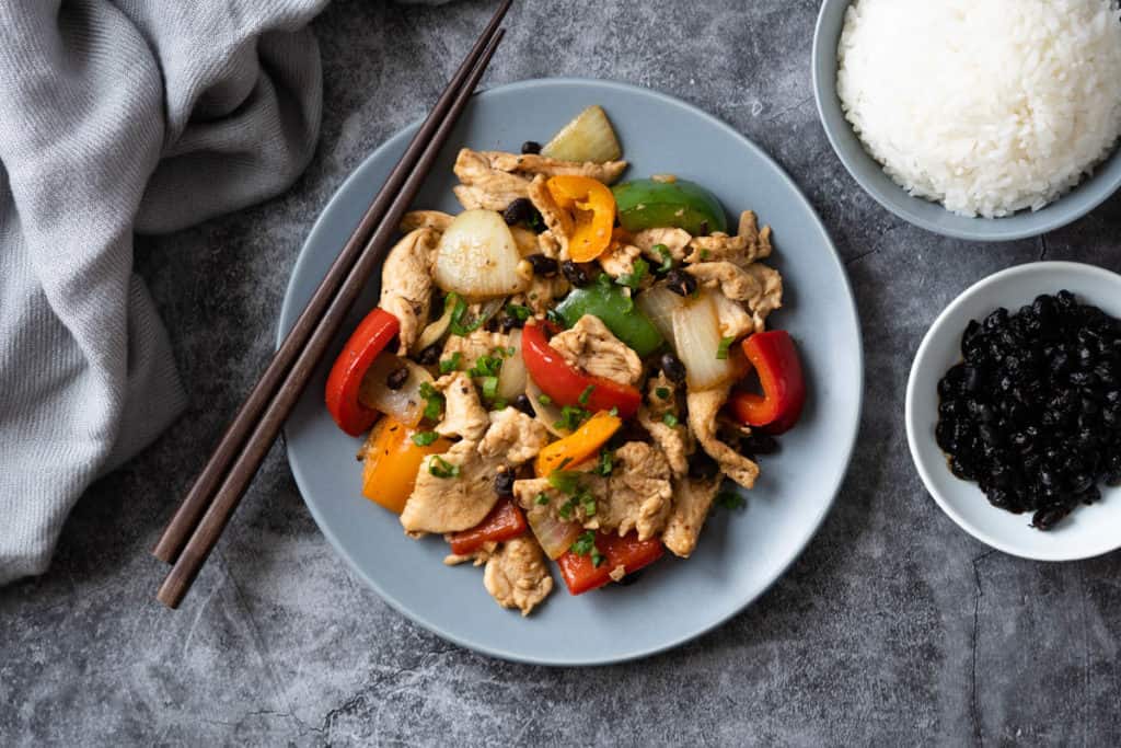 Black bean chicken breast stir fry on a plate with steamed rice.