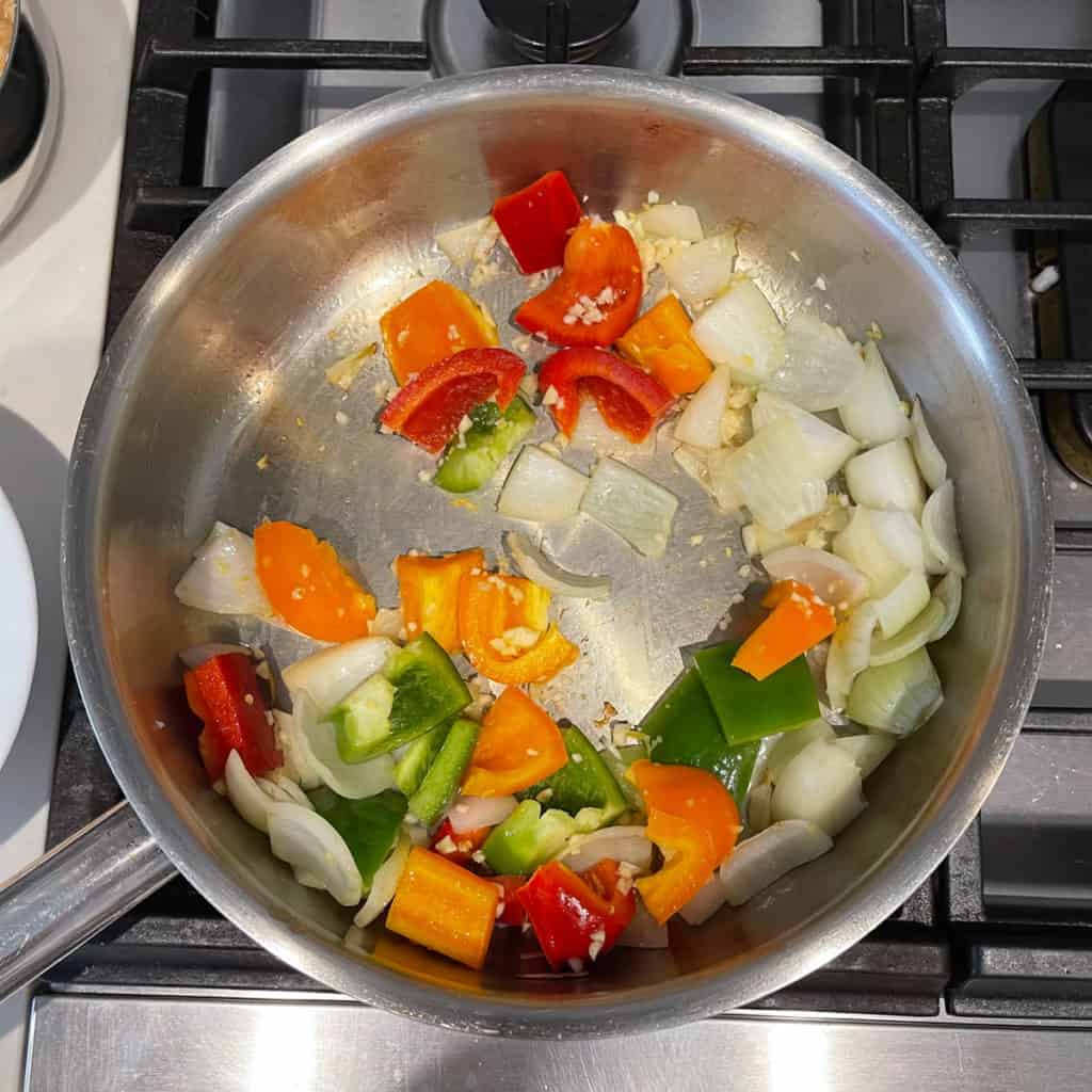 Peppers, onions and garlic frying in pan.
