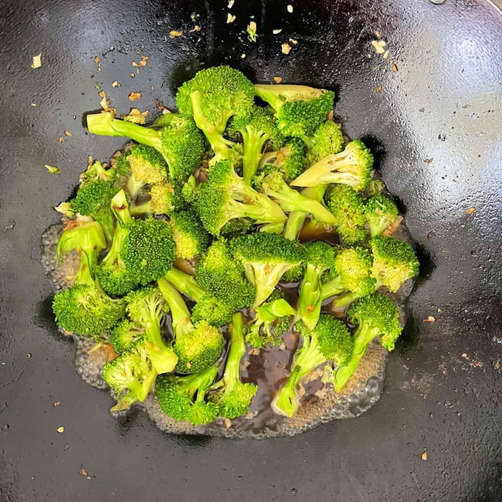 Broccoli florets simmering in sauce.