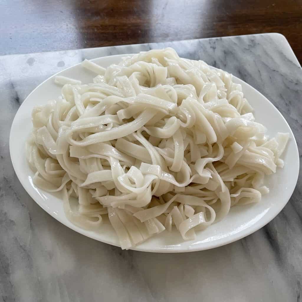 Plate of loose rice noodles ready for frying.
