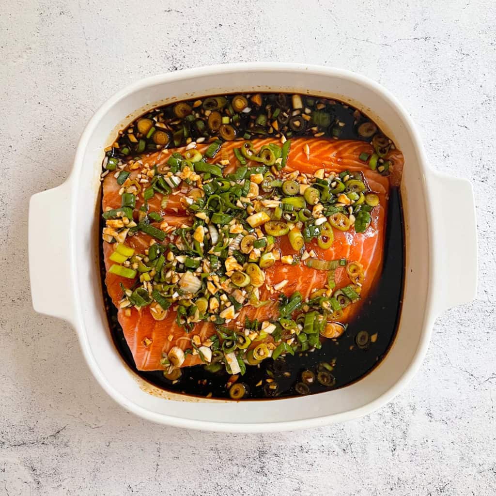 Soy maple glaze poured over a salmon fillet and marinating in its baking dish.