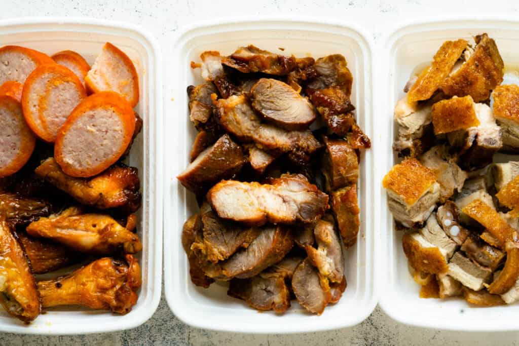 A display of Chinese barbecued meats in their takeout containers.